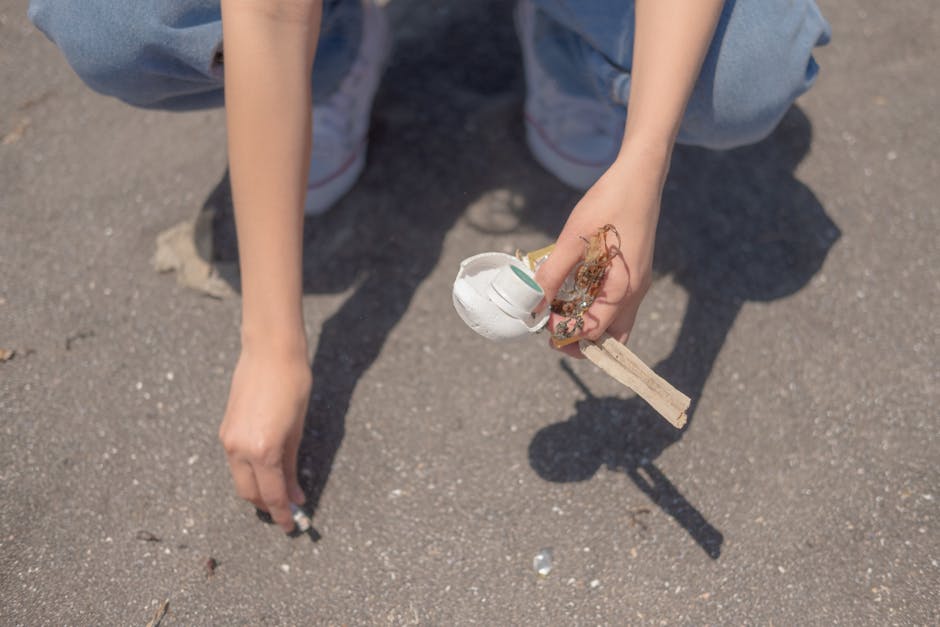 Photograph of a pile of assorted waste materials placed on an outdoor concrete pavement area, possibly for rubbish removal or clearance services. The foreground features a collection of discarded item